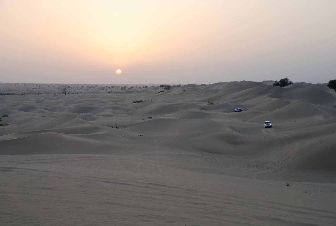 Sunset over the dunes with 4x4 vehicles in the distance