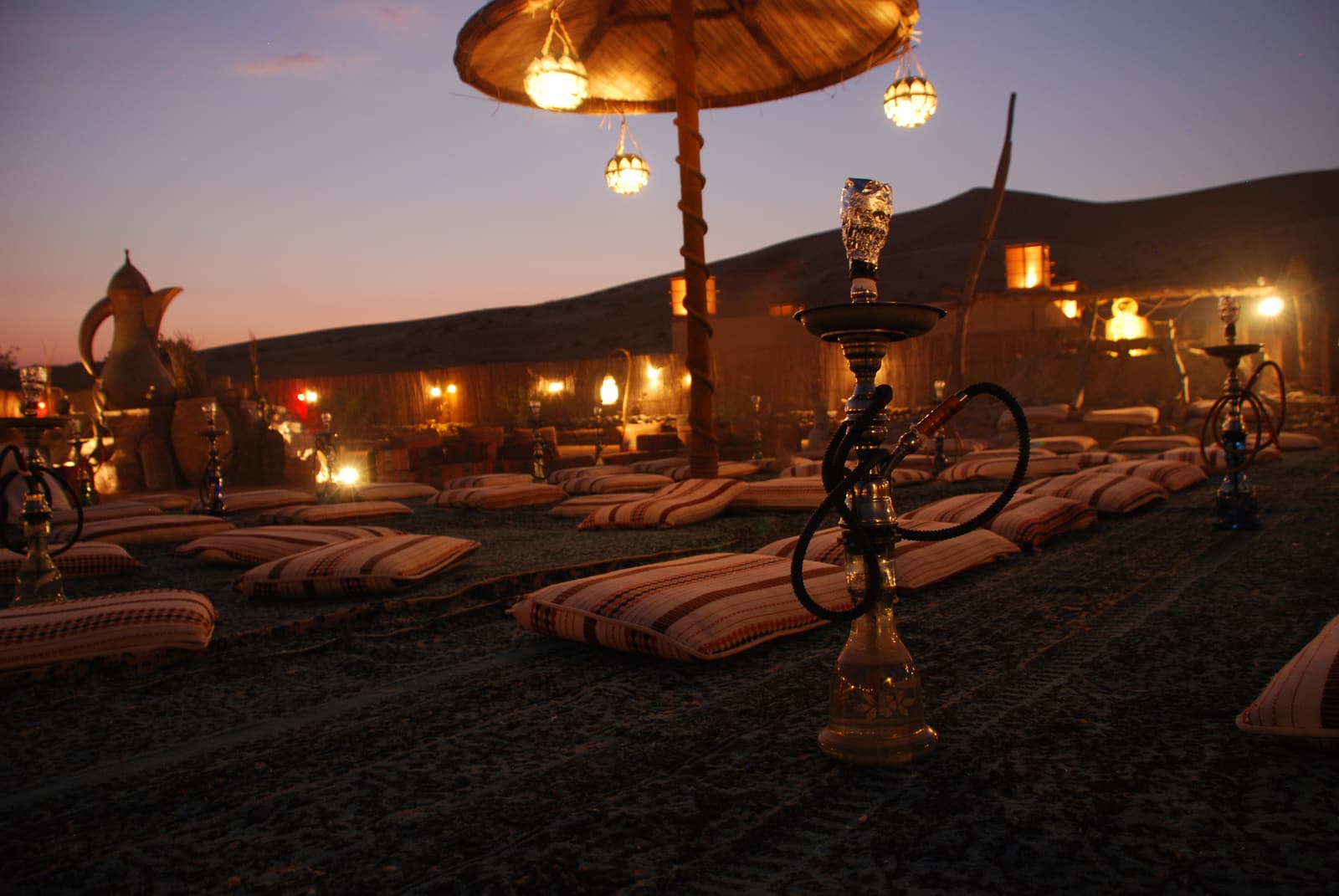 Cushions and low tables set out in a desert camp at dusk