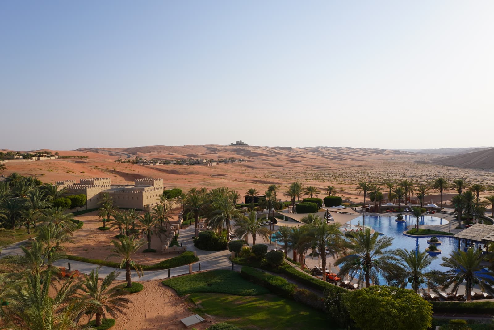 The pool of a desert resort surrounded by dunes