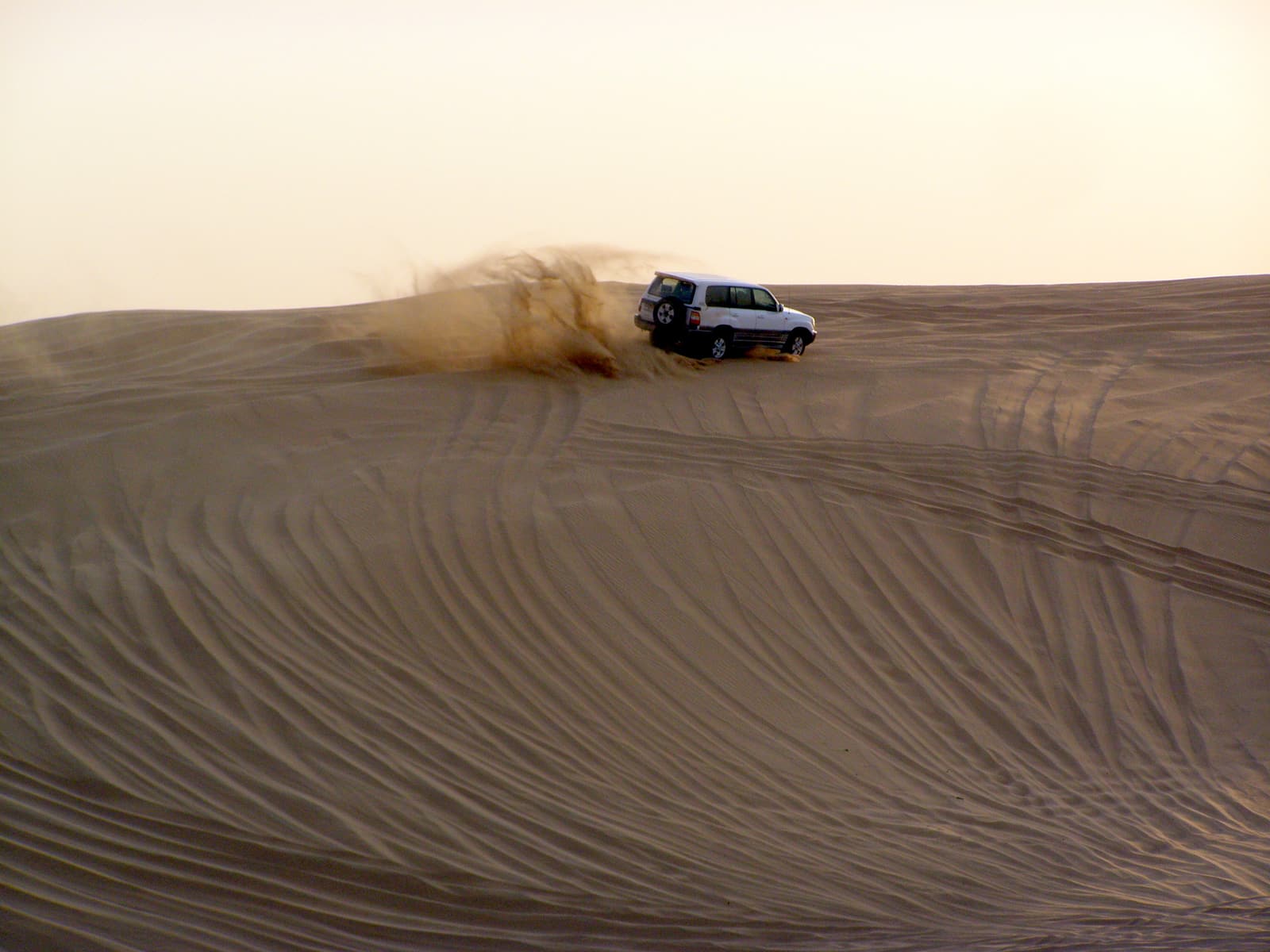 A 4x4 throwing up sand on a dune drive