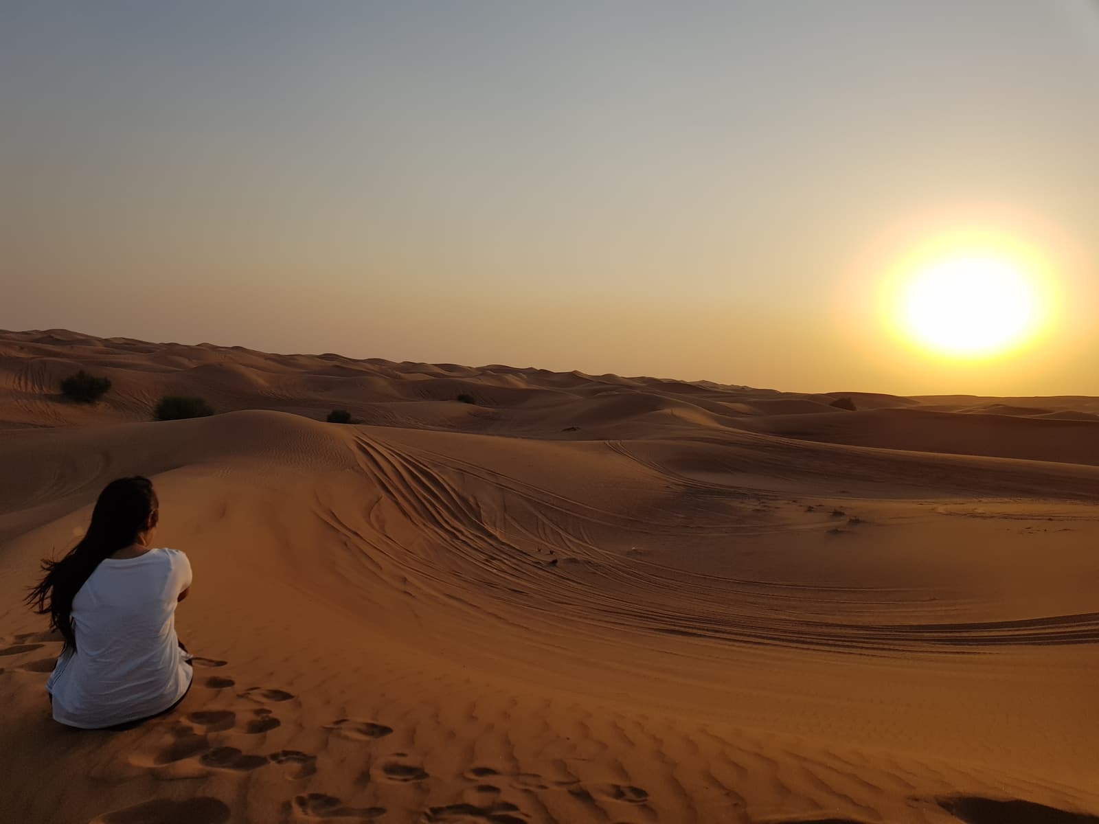 A visitor watching the sun set over the dunes