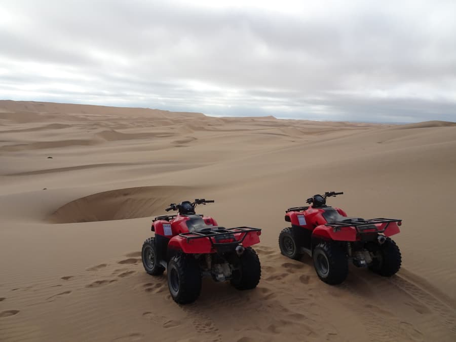 Two quad bikes parked on a sand dune