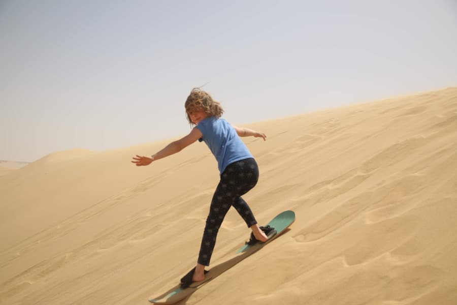 A sandboarder sliding down a dune